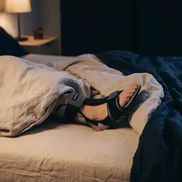 DorsalFlex night splint worn in bed — open heel, free toes, low-profile fit under blankets